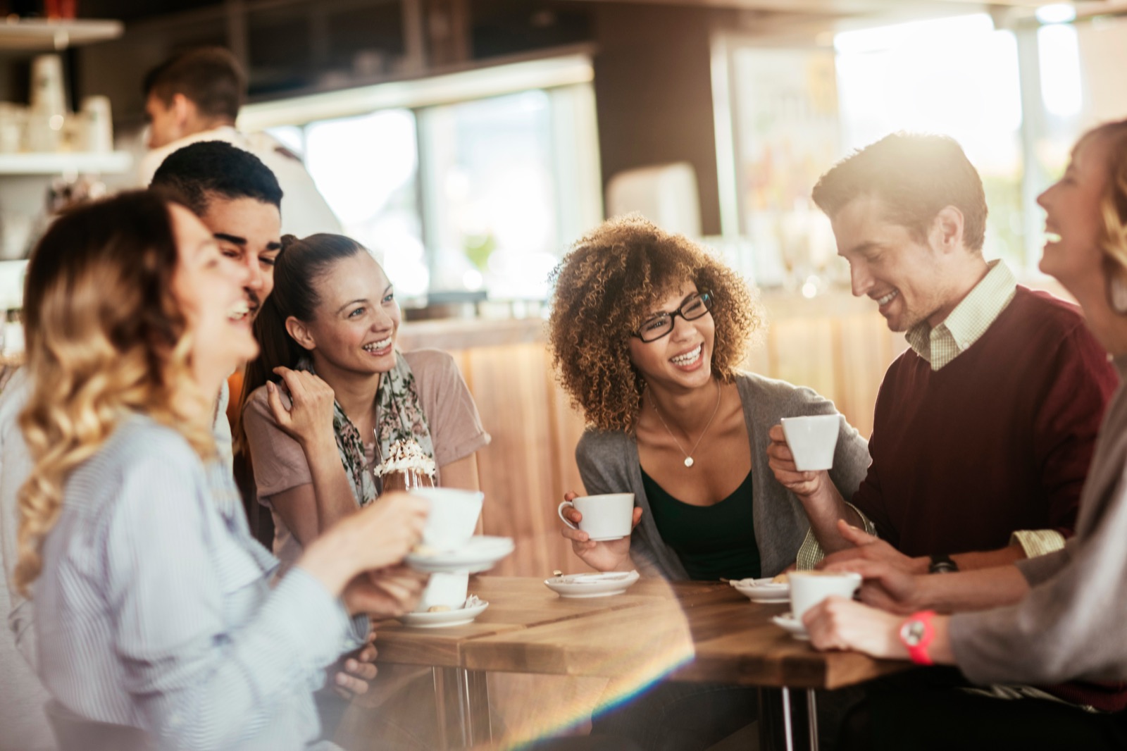 Friends laughing together over coffee at a café